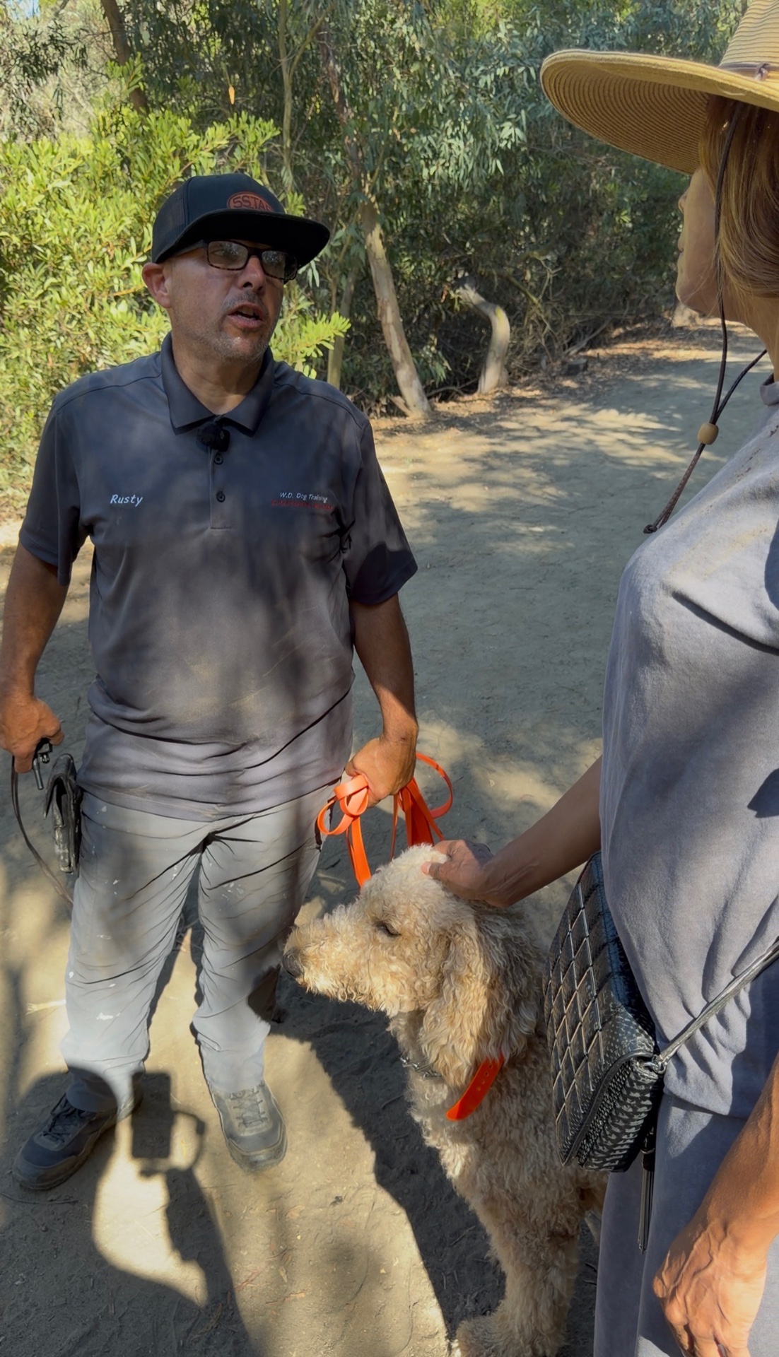 Rusty talking with a client and her Goldendoodle on the trail